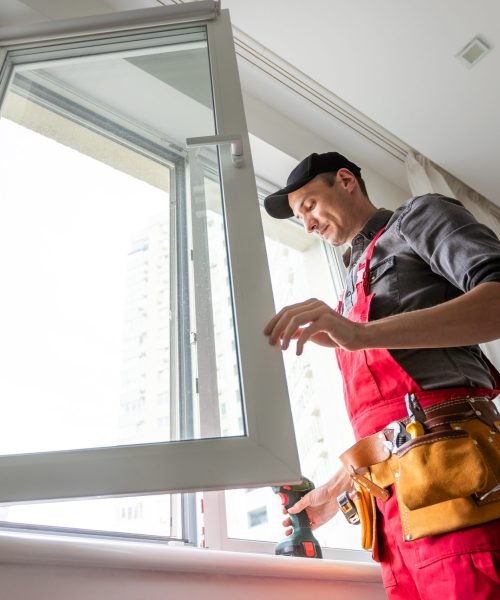 craftsmen workers install a window in the house rattle with a special rubber hammer. High quality photo